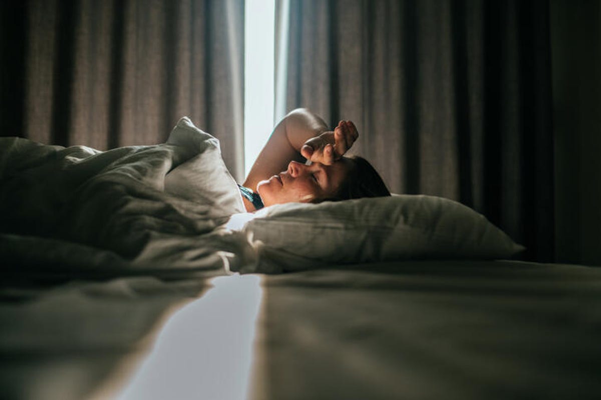 Woman waking up while in a hotel room.