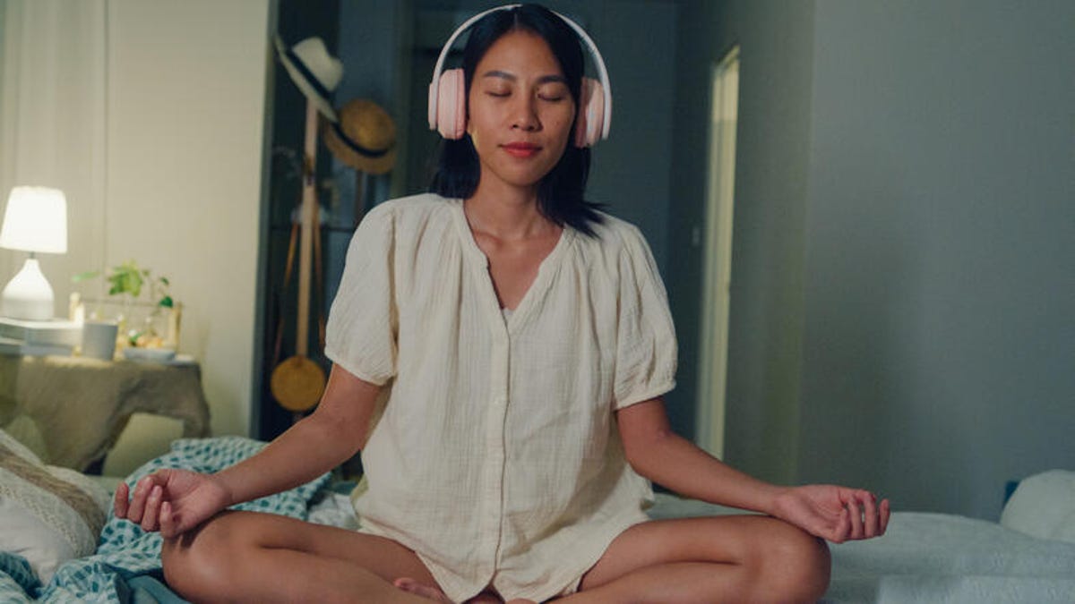 Person listening to music while meditating in bed.